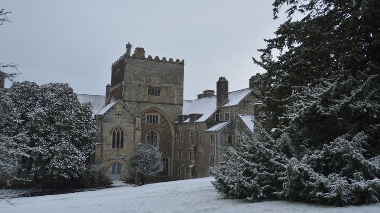 A view of the south face of the Abbey from the lawn. Snow covers the grass and trees.